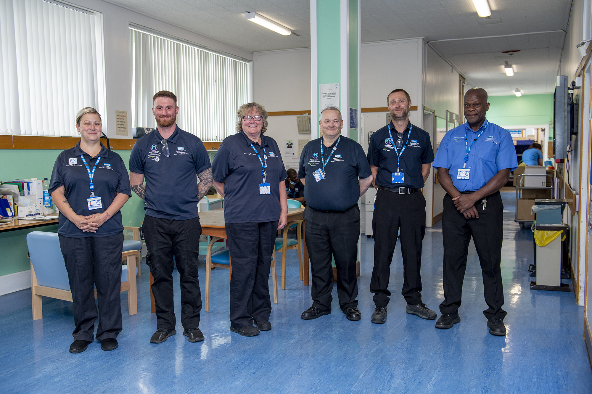 Multiple members of staff (both male and female) stood in a line inside a hospital.