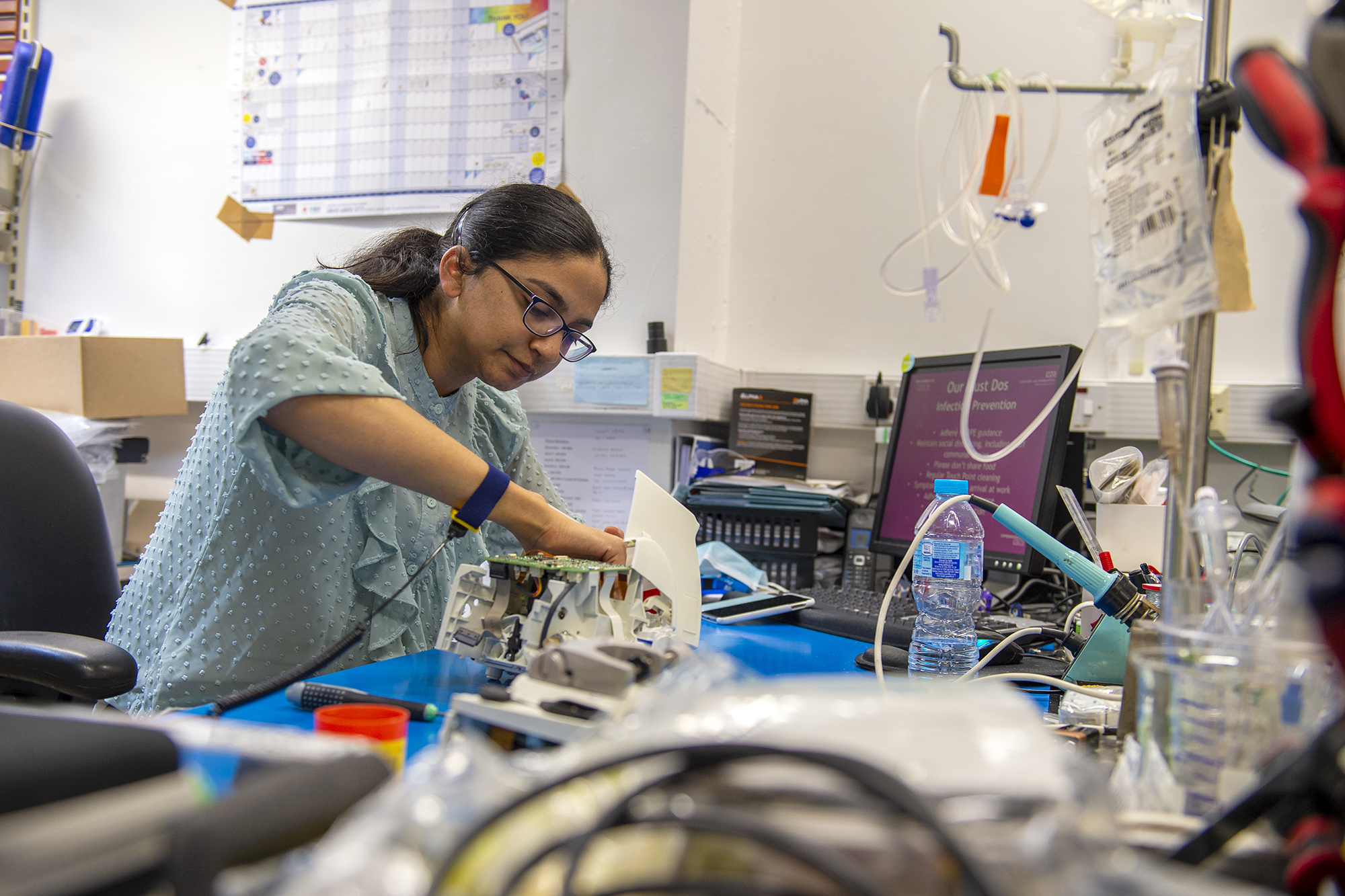 Female member of staff working with electrical equipment in a workshop. 
