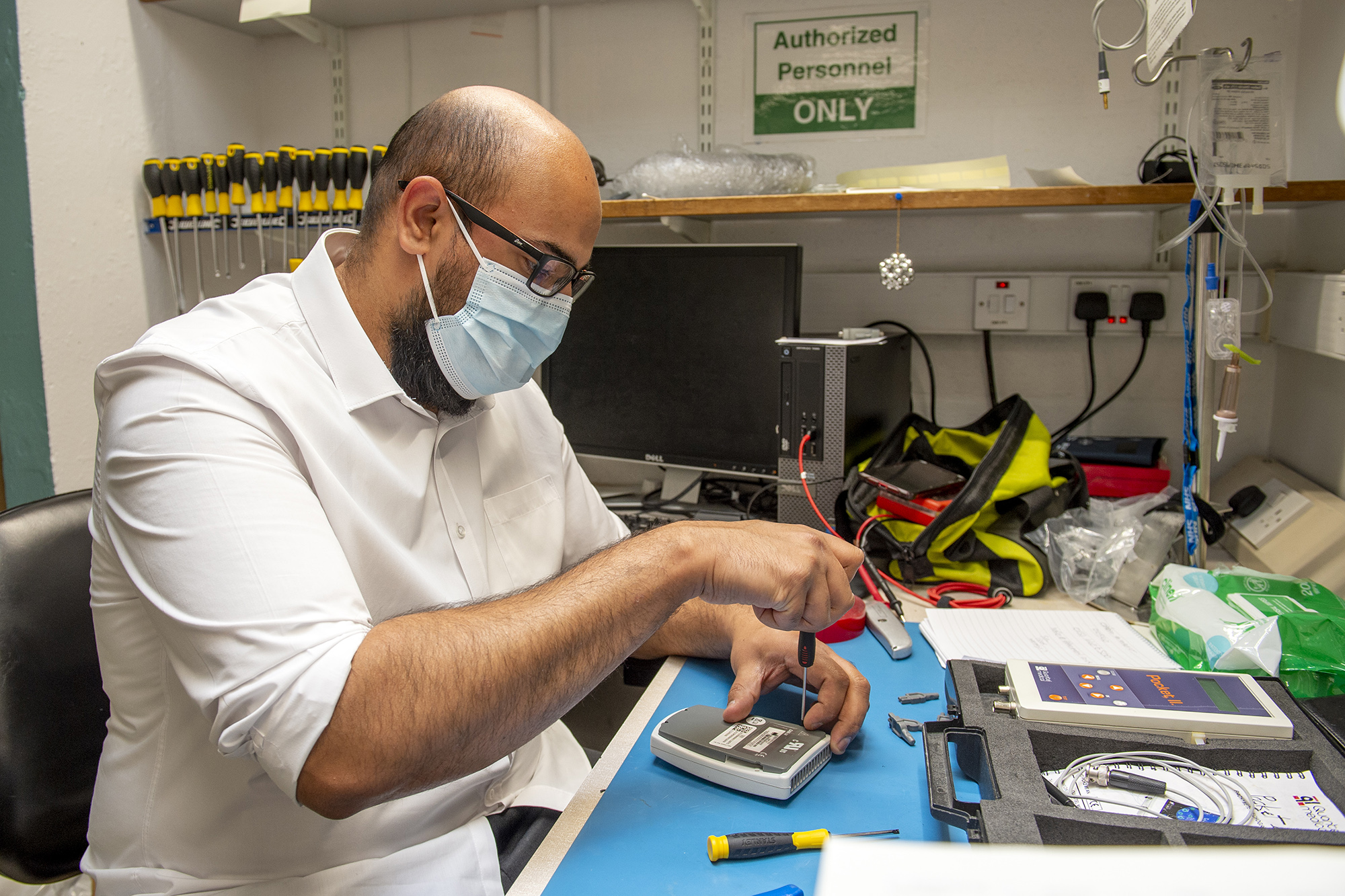 Male staff member fixing equipment wearing PPE.