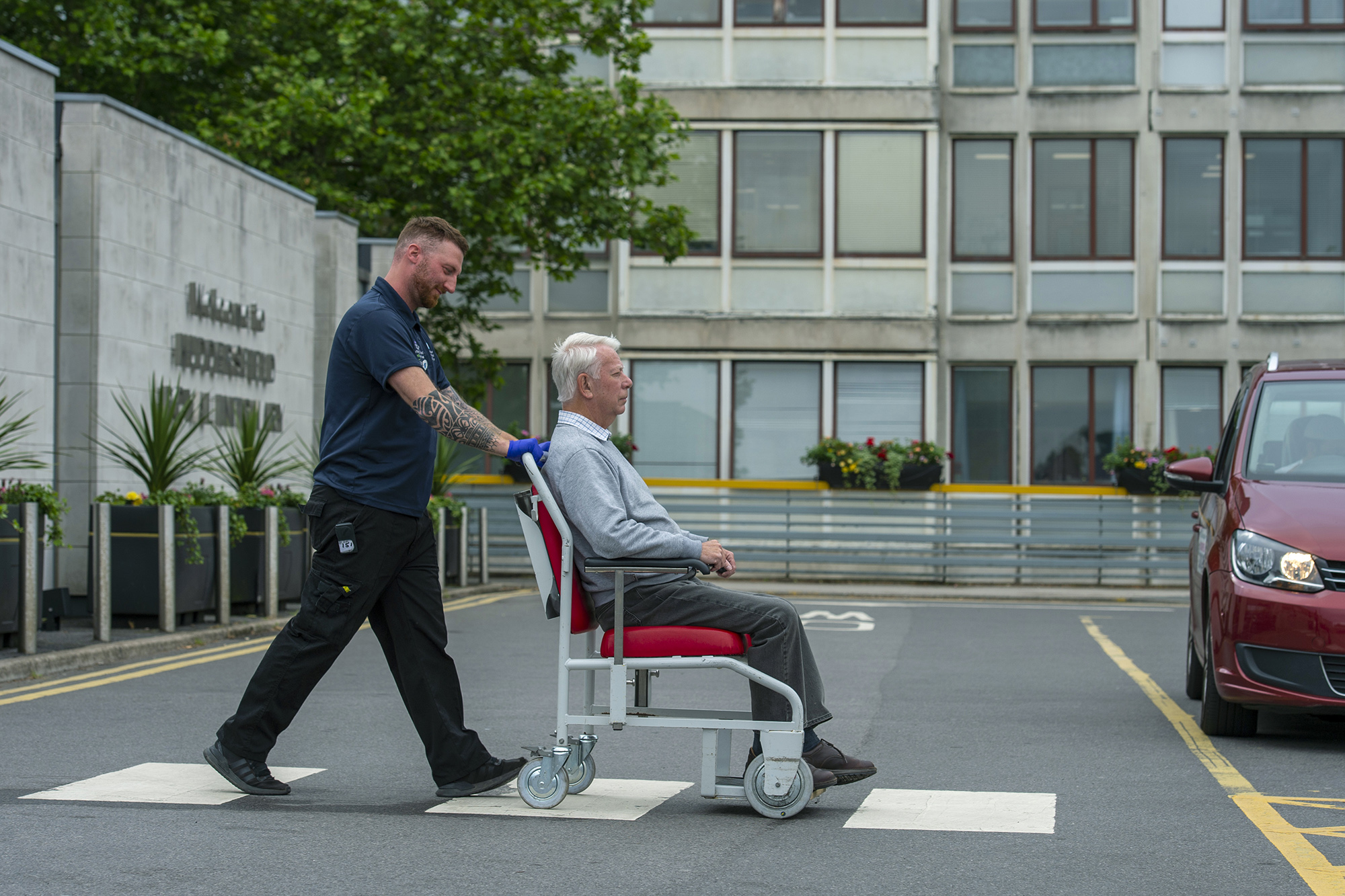 Elderly man in a wheelchair being pushed by a member of staff.