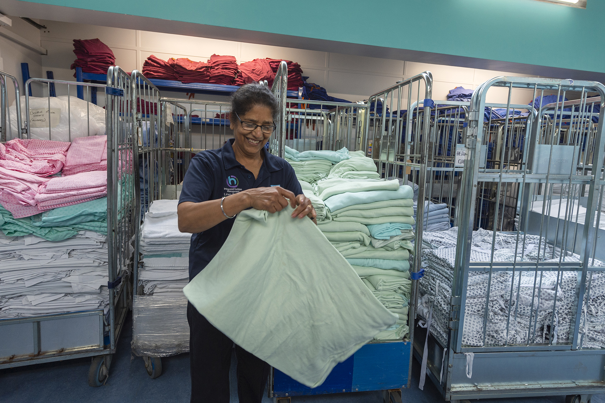 Female staff member smiling whilst folding linen. 