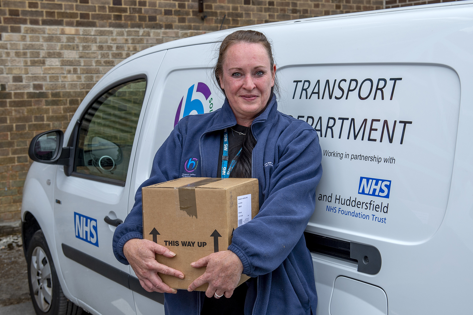 Female staff member stood next to one of our vans holding a cardboard box.