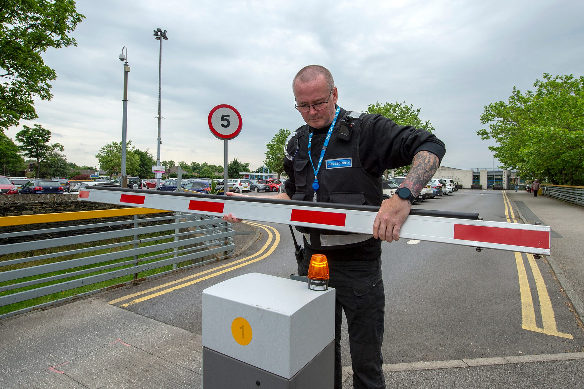 Male security guard at a hospital car park checking the barrier.