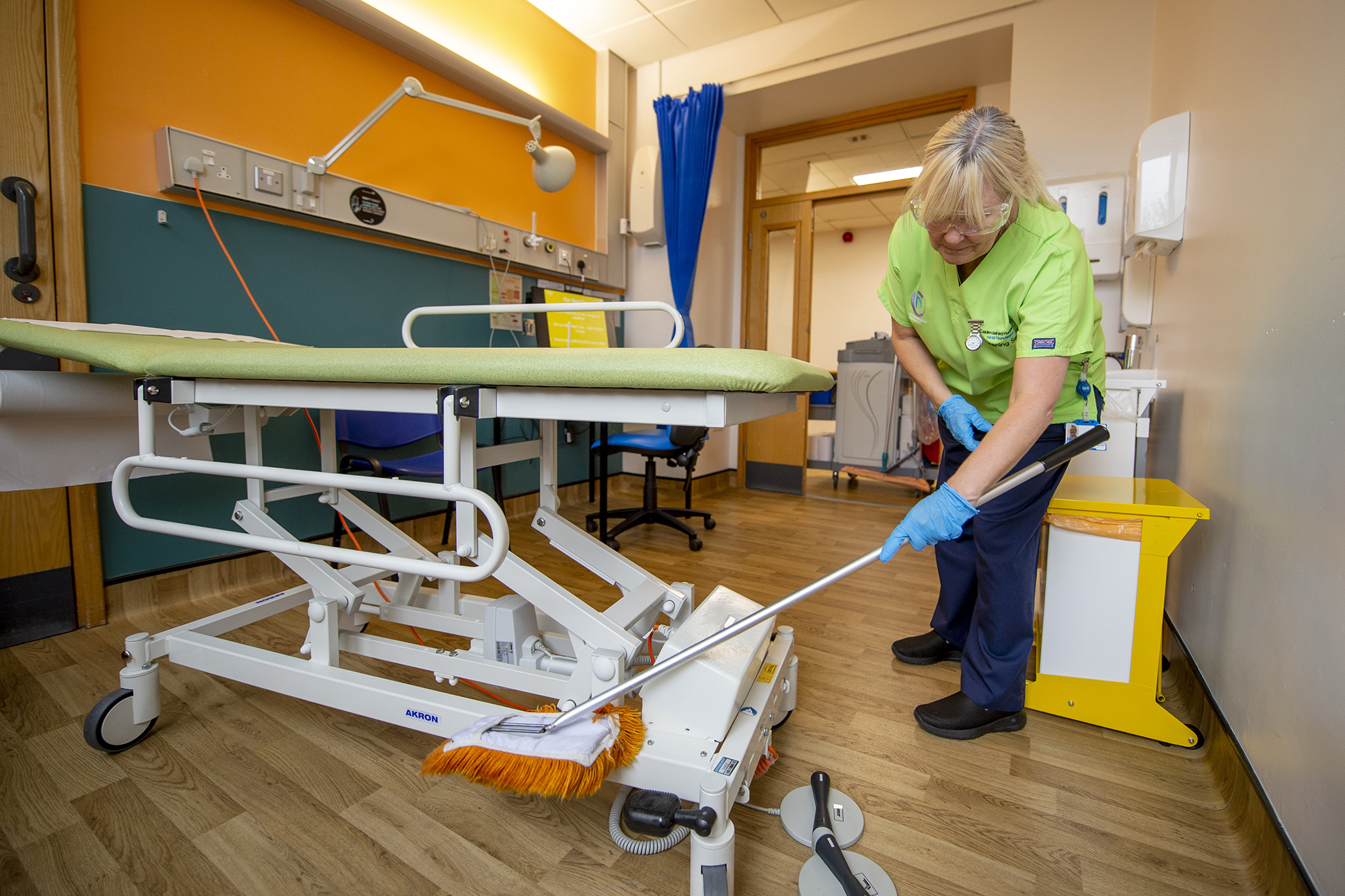 Female staff member cleaning a hospital bed.